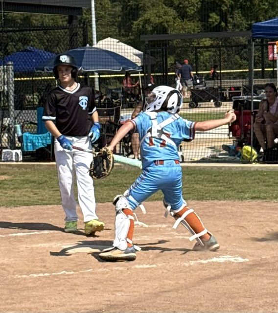 An 11U National runner crossing home plate in the light blue alternates